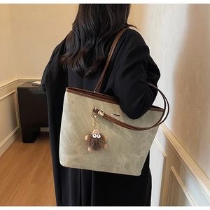 Detailed view of large grey marble tote bag with brown trim and cute plush bear charm