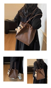 Detail view of brown pebbled leather tote bag featuring a cute beige bear charm pendant