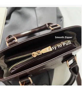 Close-up of smooth gold zipper compartment and grey lining in dark brown handbag
