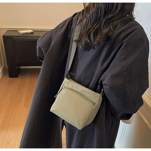 Close-up of sage green canvas crossbody bag showing texture and adjustable strap