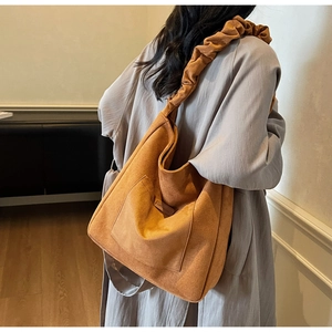 Detail of caramel suede hobo bag with a stylish pleated scrunchie shoulder strap