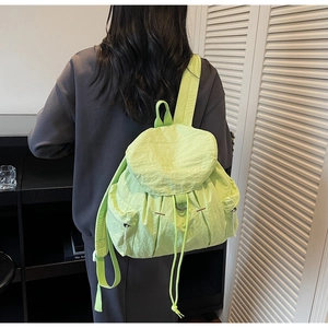 Detalle macro de la mochila de nailon verde neón con solapa con cordón y bolsillos con cremallera