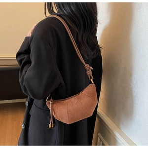 Dettaglio borsa a mezzaluna marrone con cuciture decorative e nodo sulla tracolla