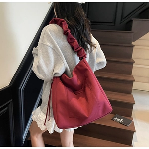 Detail of burgundy canvas bucket bag with ruffled shoulder strap and drawstring accents
