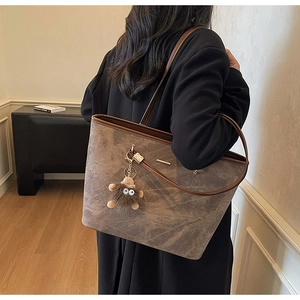 Detail of large tote bag with brown marble texture and plush doll charm accessory