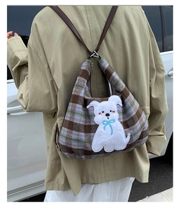 Detail of checkered tote bag with 3D white dog patch and leather shoulder straps