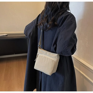 Detail of light beige canvas crossbody bag showing smooth texture and adjustable strap