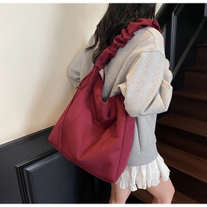 Detail of burgundy tote bag with ruffled strap and large front pocket for daily use
