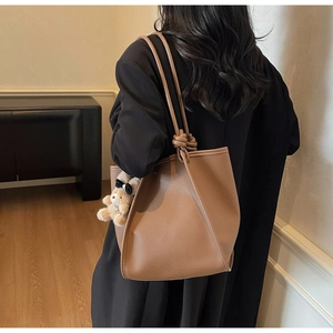Brown litchi grain leather tote bag featuring a unique knotted strap and cute bear charm