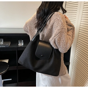 Detail of large black commute tote bag with leather flap and metallic snap closure