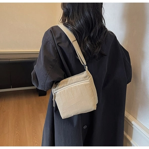 Detail of khaki canvas crossbody bag on model showing adjustable strap and texture
