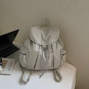 Detalle de mochila de nailon gris claro con tela texturizada y bolsillo lateral con cremallera