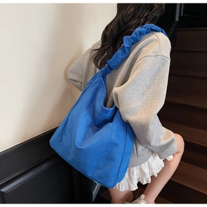 Deep blue canvas bucket bag with wide pleated shoulder strap for stylish daily commuting