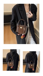 Detail of coffee brown bucket bag showing leather stitching and decorative fuzzy ball