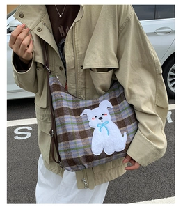 Detail of plaid tote bag with cute cartoon dog patch and brown leather shoulder strap