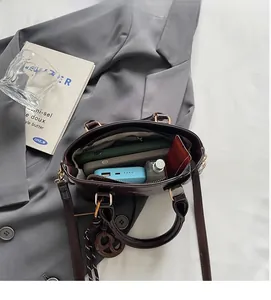 Top view of deep brown leather bag showing spacious interior with phone and perfume