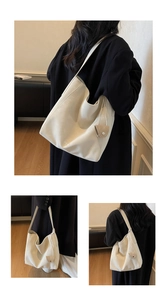 Détail d'un grand sac bandoulière crème avec un petit pendentif porte-monnaie rond