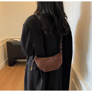 Vista posteriore di una modella con borsa a mezzaluna in camoscio marrone scuro e cuciture