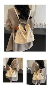 Detail of star-shaped metal zipper and plush bear charm on creamy white PU backpack