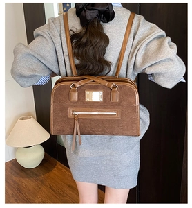Detail of vintage brown suede and leather patchwork shoulder bag with metal nameplate