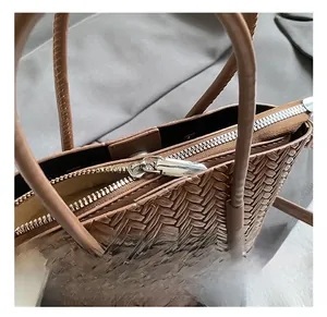 Close-up of the silver metal zipper and intricate woven texture on a brown shoulder bag