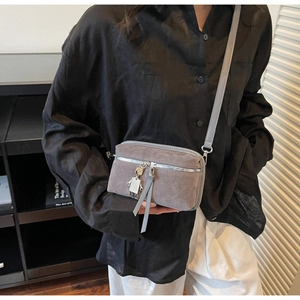 Close-up of grey suede mini crossbody bag featuring a silver robot metal charm