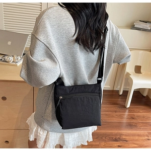 Detail of black washed canvas crossbody bag showing textured fabric and metal zipper