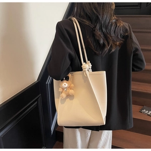 Detail of cream tote bag with pebbled leather texture and decorative knot strap detail
