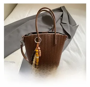 Detail view of woven brown bucket bag with colorful wooden bead tassel and long strap