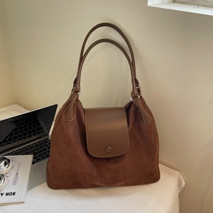 Close-up of vintage brown tote bag with suede texture and metal ring handle attachment