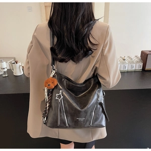 Detail of black faux leather tote bag with star zipper and plush dog pendant charm