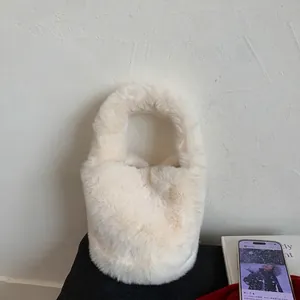 Close-up of a white plush faux fur bucket bag with a minimalist soft handle design