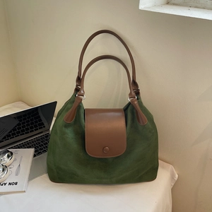 Detail of spacious dark green suede tote bag with brown leather straps for commuting