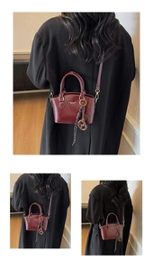 Detail view of burgundy glossy leather handbag with fine stitching and brand logo print