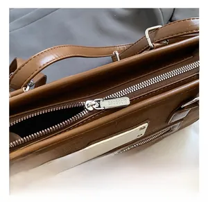 Close-up of premium silver zipper and metallic brand plate on brown leather bag