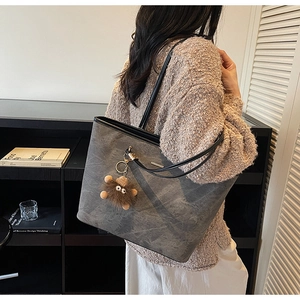 Close-up of dark grey tote bag with soft texture and a brown plush monster charm detail