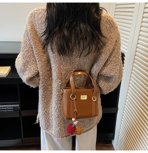 Brown vintage faux leather crossbody bag detail with plush charms and metal plaque