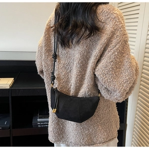 Dettaglio della borsa a mezzaluna nera a pieghe indossata da una modella in un interno