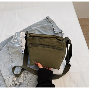 Detailed shot of an olive green nylon crossbody bag with zipper and wide strap