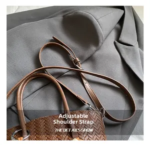 Detail shot of a brown woven PU leather bag with an adjustable shoulder strap and silver hooks