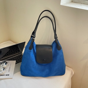 Detail of blue suede tote bag featuring black leather flap and slim shoulder straps