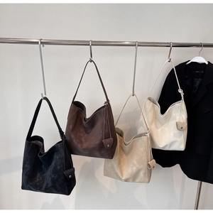 Vue détaillée de grands sacs cabas en quatre couleurs suspendus à un support métallique