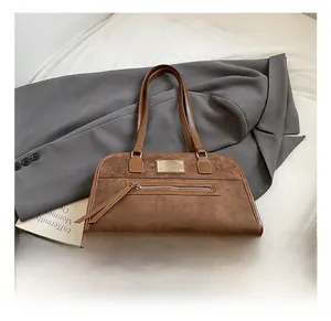 Close-up of brown suede and smooth leather stitching with twin tassel zippers