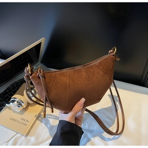 Dettaglio della texture della borsa croissant in pelle scamosciata marrone con cerniera