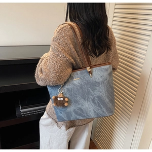 Detail of grey marble texture tote bag with brown straps and plush charm on shoulder