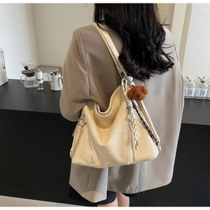 Close-up of cream PU leather tote bag with star zippers and cute bear pendant