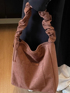 Minimalist brown suede hobo bag with pleated shoulder strap and front pocket