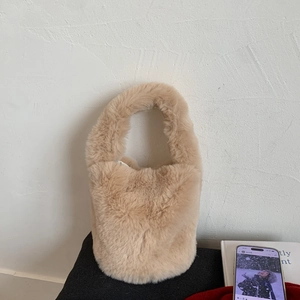 Detailed close-up of fluffy beige faux fur texture on a stylish bucket handbag