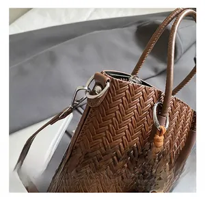 Close-up of woven brown handbag showing silver metal swivel hook and bead charm