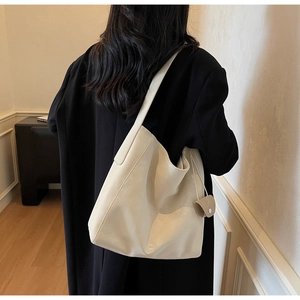 Détail d'un grand sac à bandoulière en cuir beige montrant la taille et le profil sur modèle